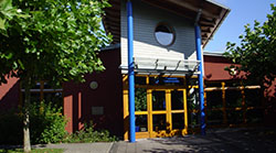 Außenansicht eines Gebäudes mit gelber Tür und blauen Eingangssäulen